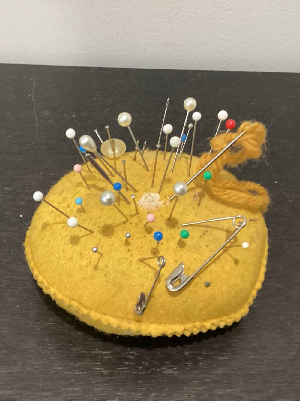 Vtg. Yellow Feltman pincushion with multiple sewing pins, safety pins, needles